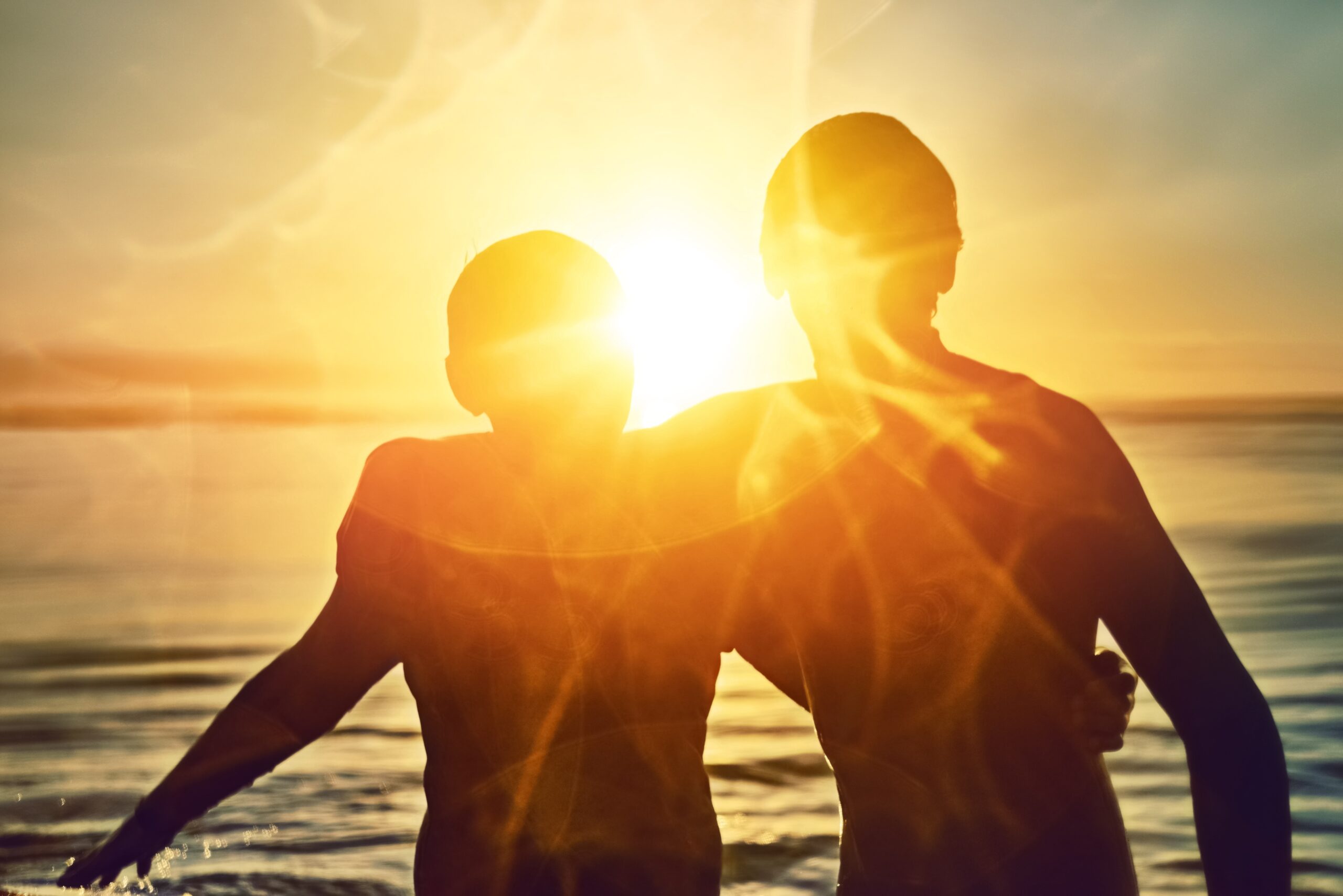 Silhouetted soldiers saluting at sunset with a large American flag blended into the sky background.